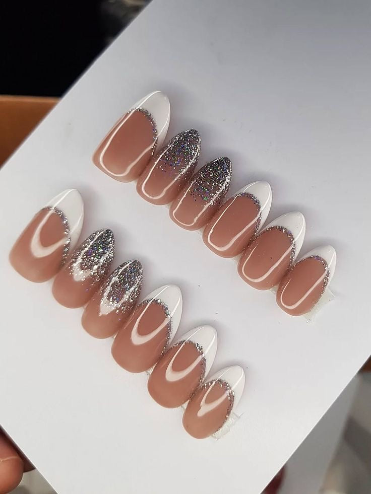 Black and nude stiletto press-on nails with rhinestone clusters in a clear case